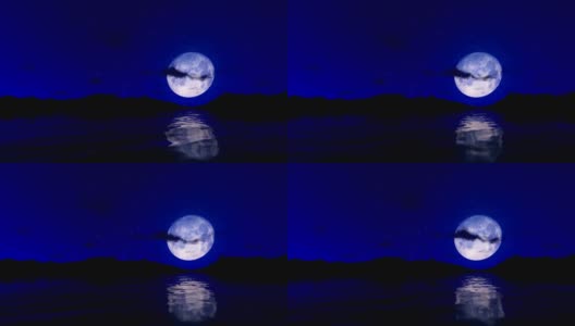 这是一个浪漫的场景，满月倒映在水面上，映衬着星空和流云高清在线视频素材下载