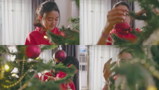 近距离亚洲少女享受装饰圣诞树在家里的客厅在圣诞节的假期。美女挂红球。高清在线视频素材下载