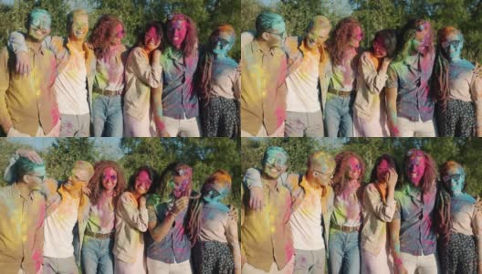 在胡里节期间，快乐的朋友们的画像，他们有着五颜六色的脸、头发和衣服，站在户外微笑高清在线视频素材下载