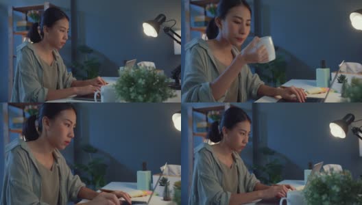 年轻的自由职业者亚洲妇女使用笔记本电脑和喝咖啡在家里的客厅晚上。高清在线视频素材下载