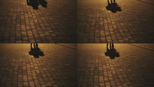 一对相爱的情侣的影子。一对情侣走在街上，人行道上两个人的轮廓和影子。高清在线视频素材下载