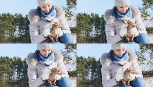 冬天，一个女人和她的小狗在外面玩耍高清在线视频素材下载