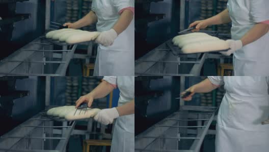 一名工人正在准备面包，准备存放和做表面切割。高清在线视频素材下载
