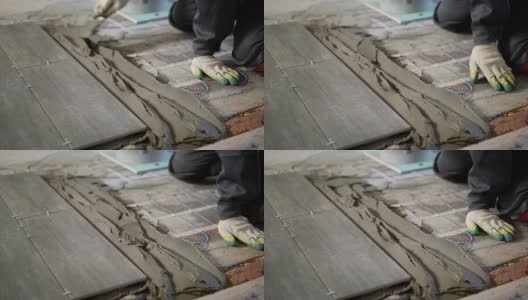 近距离拍摄的建筑工人的手在手套，谁把水泥混合物在砖地板上创造了瓷砖下的胶水高清在线视频素材下载