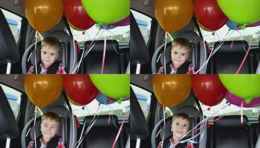 快乐的孩子在车里。喜庆心情，笑一笑，欢声笑语。汽车里的气球。孩子的生日高清在线视频素材下载