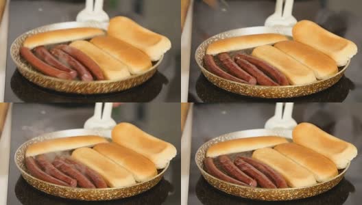 在煎锅上烤香肠和面包，同时做自制热狗高清在线视频素材下载