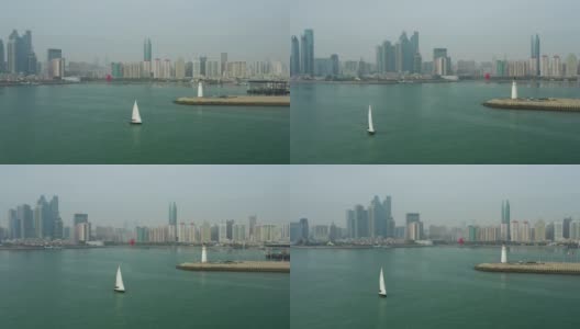 白天青岛市区海岸线湾纪念碑帆船驶过灯塔码头航拍4k中国全景高清在线视频素材下载