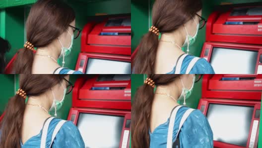 亚洲妇女戴医用口罩，使用ATM机取钱。高清在线视频素材下载