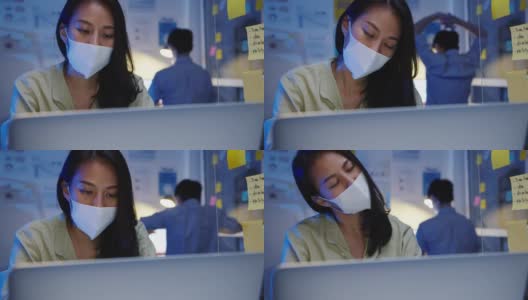 疲惫不堪的年轻亚洲女性戴着口罩用笔记本电脑工作，患有办公室综合症，颈部疼痛，在办公室加班。高清在线视频素材下载