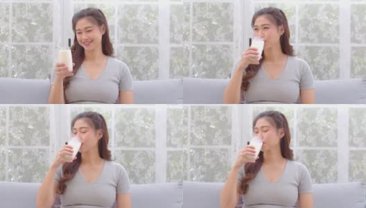 健康亚洲年轻女性在家里喝含钙牛奶强健骨骼，微笑印度女性拿着玻璃豆奶享受营养健康生活，健康与天然牛奶新鲜概念高清在线视频素材下载