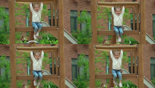 小女孩坐在操场上的滑梯上，看着相机，在绿色的夏日公园里笑个不停。快乐的孩子在户外玩耍。高清在线视频素材下载