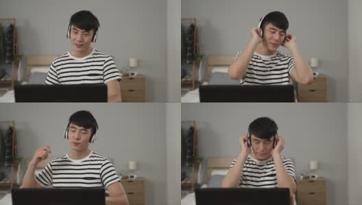 一个快乐的亚洲年轻人在家里的电脑上看在线音乐视频的时候，一边听着耳机里的歌曲，一边享受着前方镜头的慢动作。高清在线视频素材下载