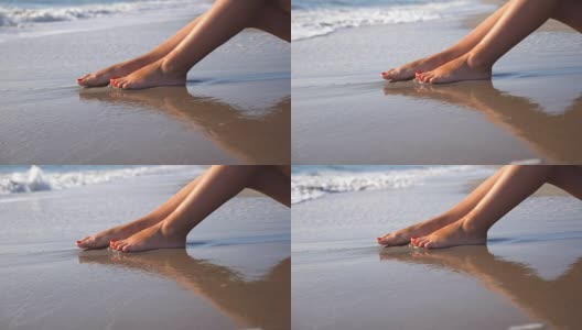 美丽的女性的腿躺在沙滩上，放松在海边。在阳光明媚的日子里，一个面目全非的年轻女子坐在海边晒太阳。度假胜地女孩的脚。暑假或假日概念。关闭侧视图慢动作高清在线视频素材下载