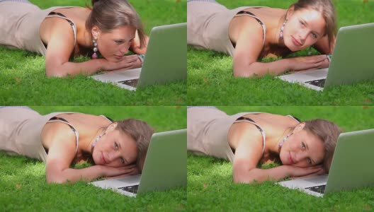 快乐的学生躺在草地上看笔记本电脑高清在线视频素材下载