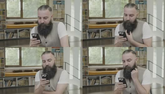 一个留着胡子的年轻人在他的智能手机上看到的东西表示赞同，并点头表示赞同高清在线视频素材下载