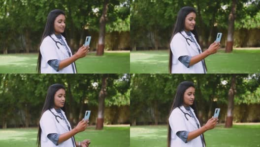 年轻的印度女医生提供远程医疗援助的肖像视频，看着摄像机，通过视频通话应用程序与临床病人交谈。现代技术，医学，远程医疗高清在线视频素材下载