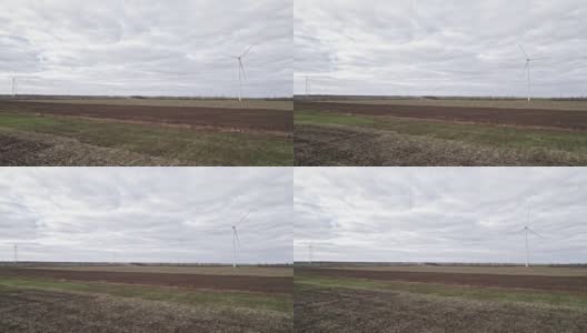 在田间的大农场全速转动叶片。旋转的风车在灰色的天空背景。由风力涡轮机产生的清洁可再生能源。另一种生活方式高清在线视频素材下载