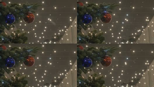 新年球挂在圣诞树上，彩色的灯。红球，街树，白雪覆盖。高清在线视频素材下载