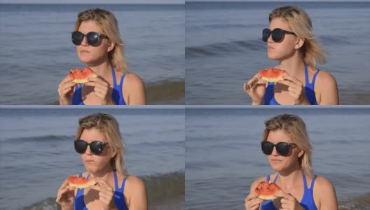 一个戴墨镜的女人坐在海滩上吃西瓜。一个金发女郎手里拿着一个成熟的西瓜高清在线视频素材下载