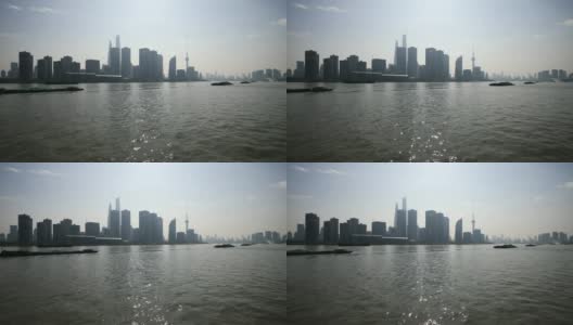 从渡轮、摩天大楼和地标建筑上观看上海外滩，蓝天背景，货船在黄浦江上航行，4K视频，慢镜头。高清在线视频素材下载