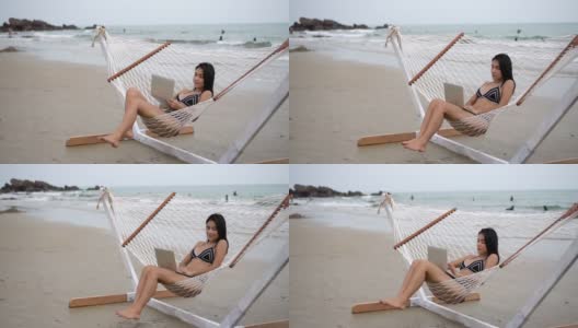 侧视图比基尼女孩使用笔记本电脑在海滩上的拷贝空间高清在线视频素材下载