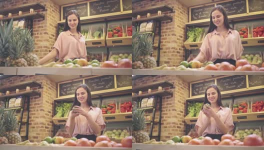 一个棕色头发的女人微笑着在蔬菜水果店买水果高清在线视频素材下载