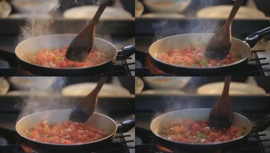 用平底锅煎西红柿和辣椒，准备饭菜，用搅拌勺搅拌食物高清在线视频素材下载