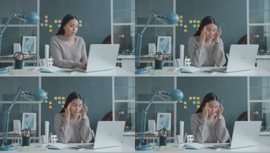 压力大的亚洲女性在办公室用笔记本电脑打字，患有偏头痛高清在线视频素材下载