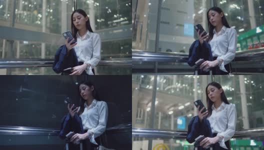 年轻的女秘书穿着正装在机场的电梯里使用智能手机高清在线视频素材下载