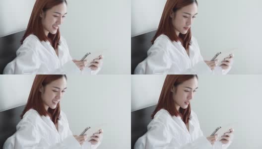 性感的女人穿白衬衫玩电脑平板电脑和微笑在卧室的特写高清在线视频素材下载