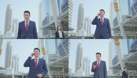 亚洲经理聪明的商人使用智能手机在城市。那人拿着电话，一边说话，一边微笑着站在户外。以电信和移动网络为经营理念。高清在线视频素材下载