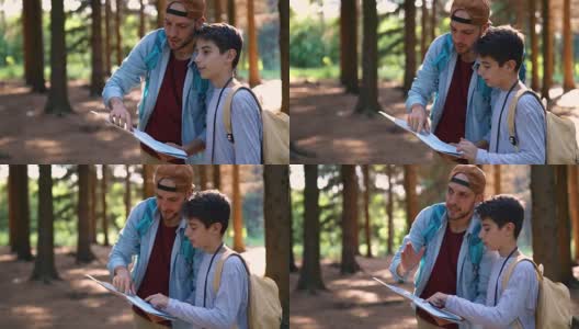 父亲和儿子在森林里看地图高清在线视频素材下载