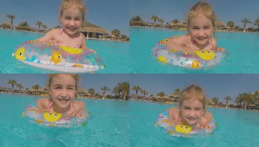 在炎热的夏日里，快乐的小女孩在室外游泳池里玩五彩缤纷的充气圈。孩子们在热带度假胜地玩耍。孩子们学游泳。家庭海滩度假。高清在线视频素材下载