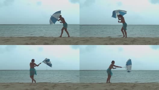 一名年轻的游客在暴风雨中挣扎着撑起雨伞。高清在线视频素材下载
