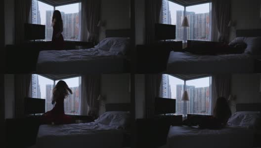 快乐女子在床上打旋跳跃，窗外香港全景高清在线视频素材下载