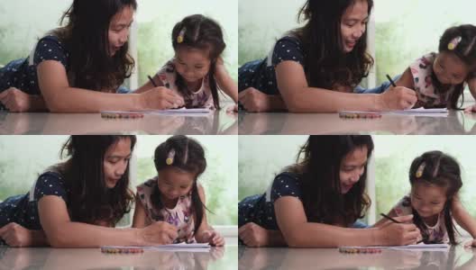 年轻的妈妈和可爱的女儿喜欢用铅笔画彩色图画。幸福家庭与儿童发展理念。高清在线视频素材下载