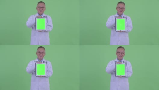 亚洲男子医生的肖像微笑和显示数字平板电脑与复制空间的绿色背景高清在线视频素材下载