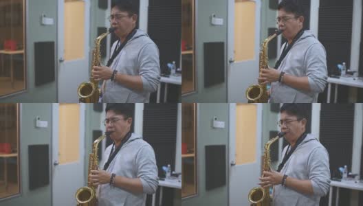 亚洲华人中年男子学习乐器演奏萨克斯在音乐工作室班高清在线视频素材下载