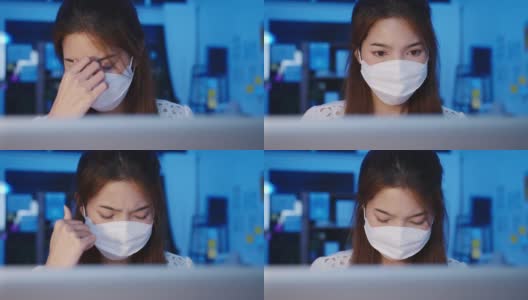 快乐亚洲女商人戴着医用口罩，在新常态下保持社交距离，以预防病毒，在办公室晚上使用笔记本电脑回到工作岗位。高清在线视频素材下载
