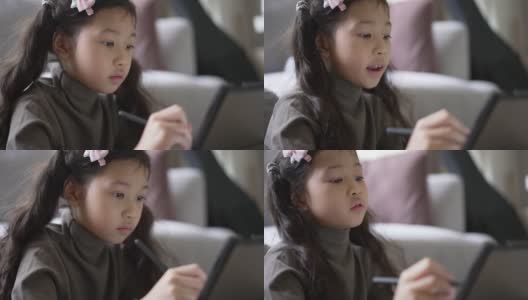 小女孩在家里客厅的沙发上用数码平板电脑在线学习高清在线视频素材下载