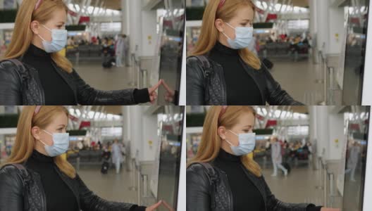 一名戴着医用口罩的妇女在机场触摸敏感屏幕。高清在线视频素材下载