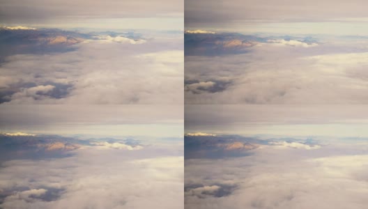 云和雪覆盖的阿尔卑斯山脉的鸟瞰图透过一架喷气式飞机的窗户在日落时分大陆飞行高清在线视频素材下载