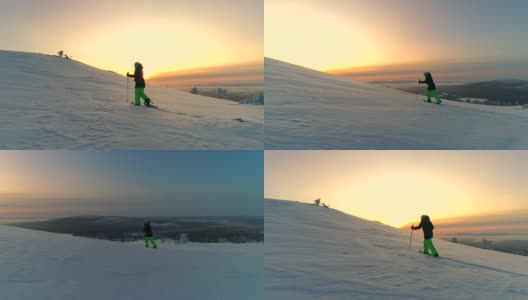 天线:在冬日的夕阳下，活跃的女性穿着雪鞋在白雪覆盖的山坡上徒步高清在线视频素材下载