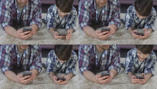 儿子和父亲躺在地板上玩智能手机，缺乏关爱高清在线视频素材下载