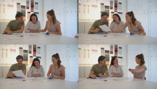 女室内设计师一边看桌子上的草图，一边向顾客夫妇提出不同的建议高清在线视频素材下载