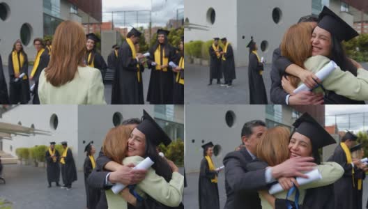 在毕业典礼上，快乐的毕业生拥抱她的父母，看起来很兴奋高清在线视频素材下载