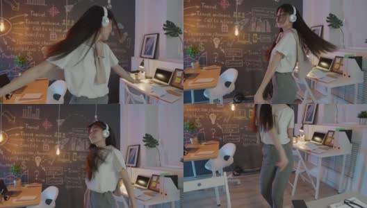 无忧无虑的亚洲女商人戴着耳机在晚上的创意办公室跳舞高清在线视频素材下载