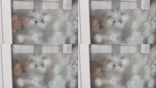 母亲和儿子用假雪装饰窗户。高清在线视频素材下载