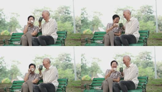 慢镜头快乐的亚洲老夫妇坐在早上的公园喝茶，喝咖啡。交谈并表达爱意高清在线视频素材下载