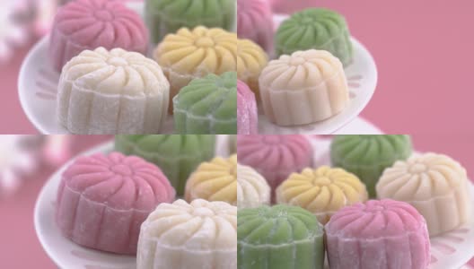 彩色的雪皮月饼，甜的雪月饼，传统美味的甜点中秋节在柔和的淡粉色的背景，近距离，生活方式。高清在线视频素材下载